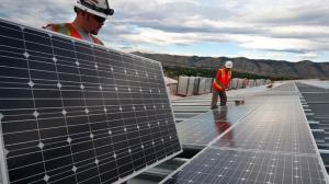 WOrkers installing solar panels on a large rooftop