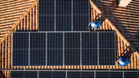 Aerial view of Two workers installing solar panels on a rooftop stock photo