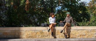 Two students sitting on a wall outside of Kroon Hall