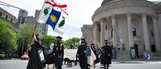 YSE graduates crossing the streeet while holding the School flag high