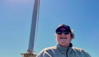 Williams in front of a large ocean wind turbine