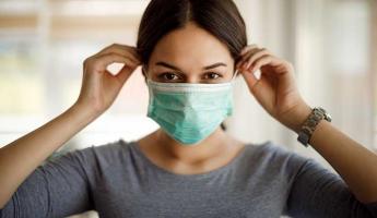 portrait of young woman putting on a protective mask
