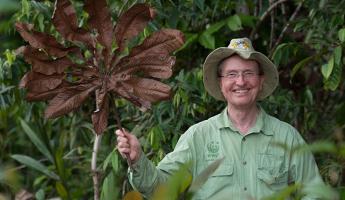 Tom Lovejoy holding up a huge tropical leaf