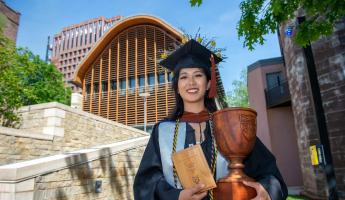 Elaine Lac holding the Kroon Cup in front of Kroon Hall