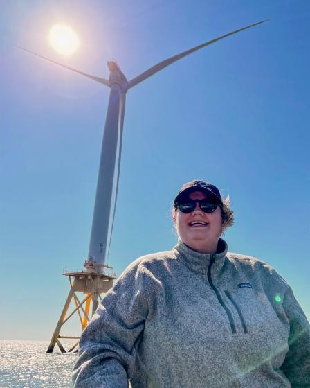 Williams in front of a large ocean wind turbine