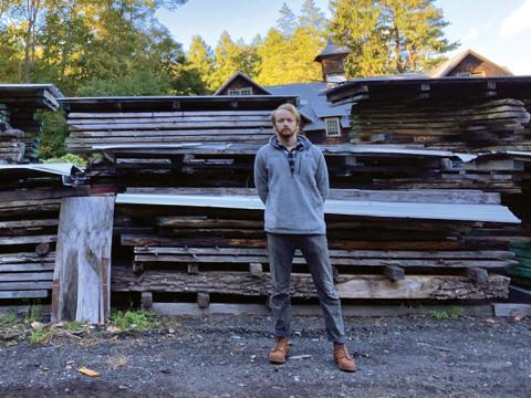 Ben Christensen standing in front of piles of weathered lumber