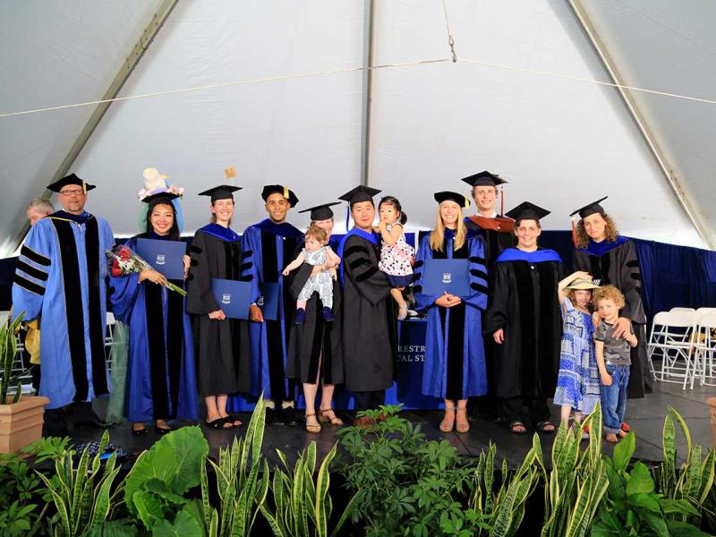 A cohort of 9 PhD graduates celebrating commencement