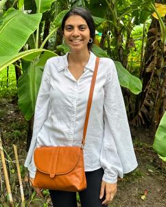 Jinali Mody with a Banofi Leather purse, standing among banana plants the purse was sourced from