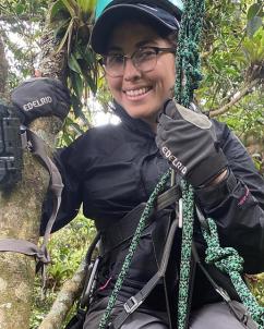 Siria Gamez in a climbing harness placing a camera in the tree tops
