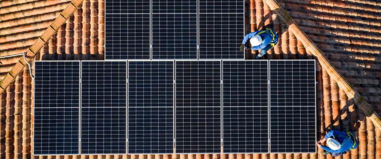 Aerial view of Two workers installing solar panels on a rooftop stock photo