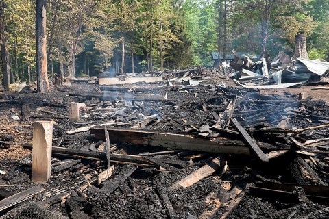 the remains of three camp buildings destroyed by fire
